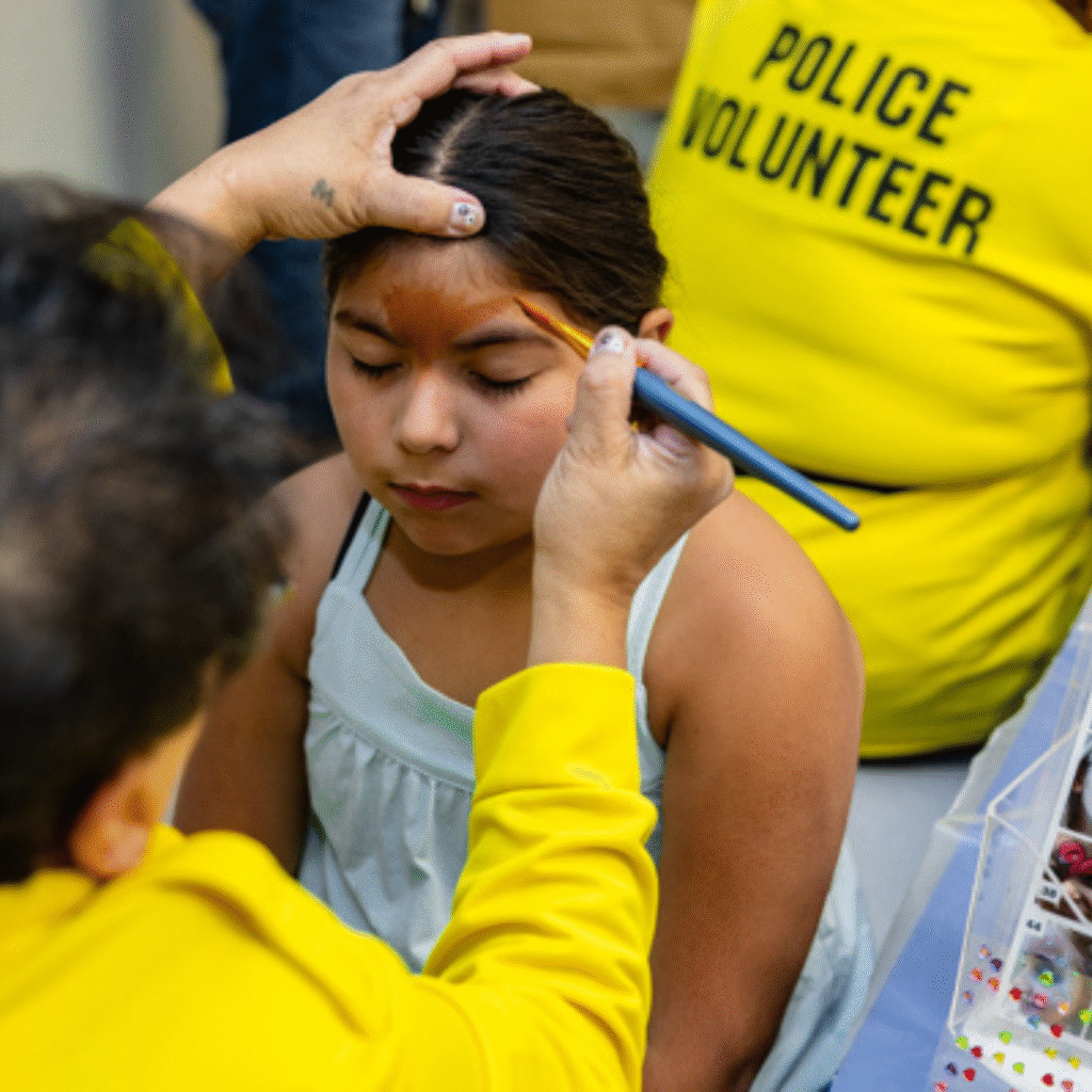 Police volunteers paint the face of students.